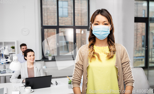 Image of asian woman in protective medical mask at office