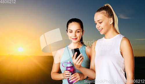 Image of women or female friends with smartphone and flask