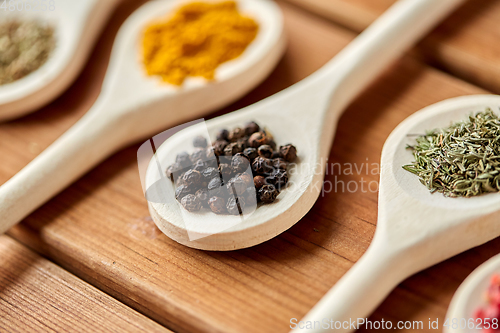 Image of spoons with different spices on wooden table