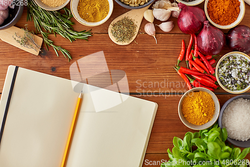 Image of notebook with pencil among spices on wooden table