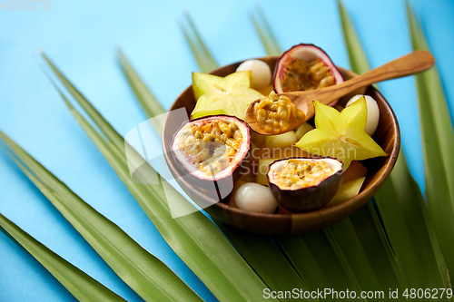 Image of mix of exotic fruits in wooden plate with spoon