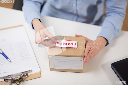 Image of woman sticking fragile mark to parcel box