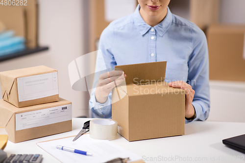 Image of woman packing parcel box at post office