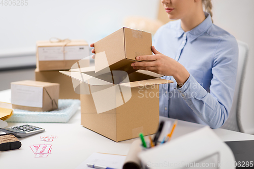 Image of woman packing parcel box at post office