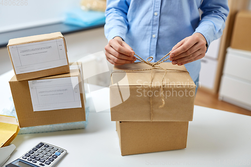 Image of woman packing parcel and tying rope at post office