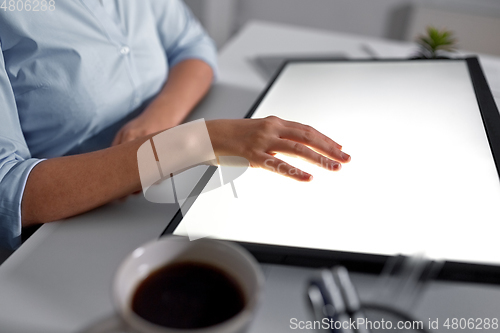 Image of hand on led light tablet at night office