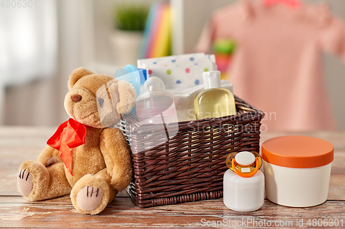 Image of baby things in basket and teddy bear toy on table