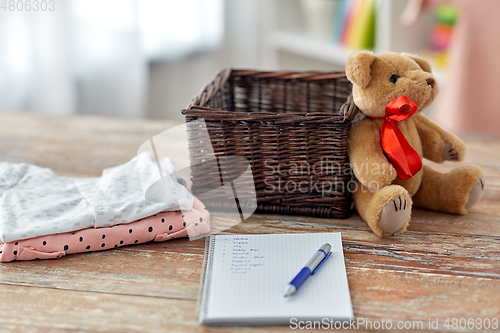 Image of baby clothes, teddy bear, toy blocks and notebook