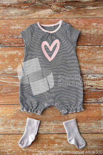 Image of baby bodysuit and socks on wooden table