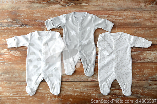 Image of baby clothes set of bodysuits on wooden table