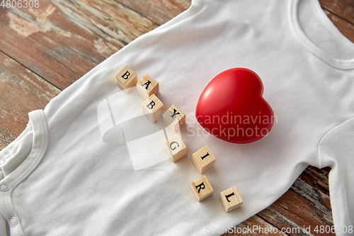 Image of baby bodysuit with red heart on wooden table