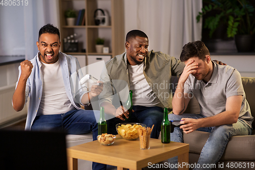 Image of happy friends playing video games at home at night