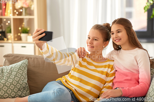 Image of happy girls taking selfie with smartphone at home