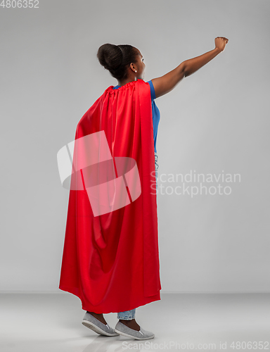 Image of happy african american woman in red superhero cape