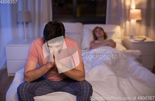 Image of sad man with insomnia sitting on bed at night
