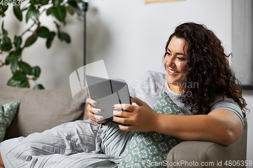 Image of woman with tablet pc computer on sofa at home