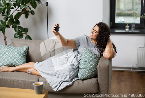Image of happy woman taking selfie with smartphone at home