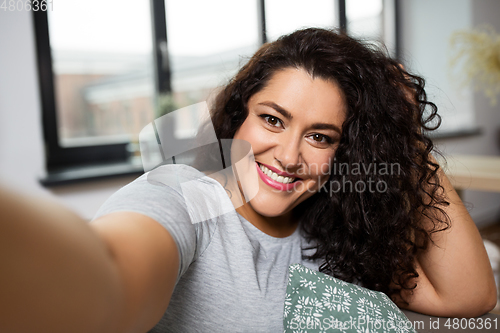 Image of happy smiling young woman taking selfie at home