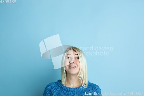Image of Portrait of young caucasian woman looks happy, dreamful on blue background