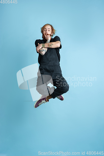 Image of Portrait of young caucasian man looks happy, jumping on blue background