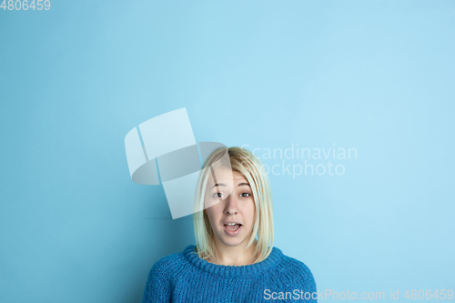 Image of Portrait of young caucasian woman looks happy, dreamful on blue background