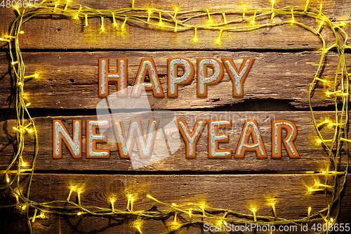 Image of New Year wishes made of cakes on wooden table background