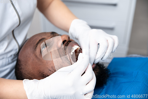 Image of Young african-american man visiting dentist\'s office