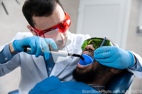 Image of Young african-american man visiting dentist\'s office