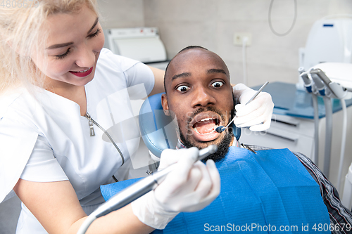 Image of Young african-american man visiting dentist\'s office, looks scared