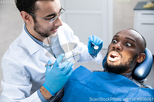 Image of Young african-american man visiting dentist\'s office