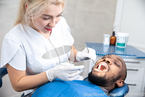 Image of Young african-american man visiting dentist\'s office