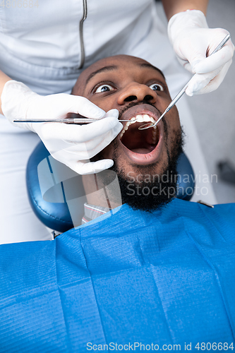 Image of Young african-american man visiting dentist\'s office, looks scared