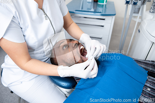 Image of Young african-american man visiting dentist\'s office