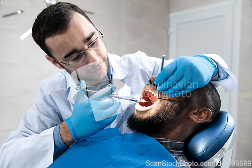 Image of Young african-american man visiting dentist\'s office