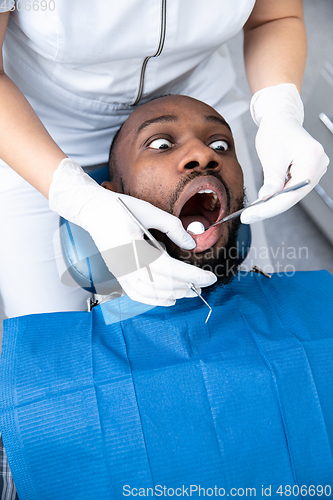 Image of Young african-american man visiting dentist\'s office