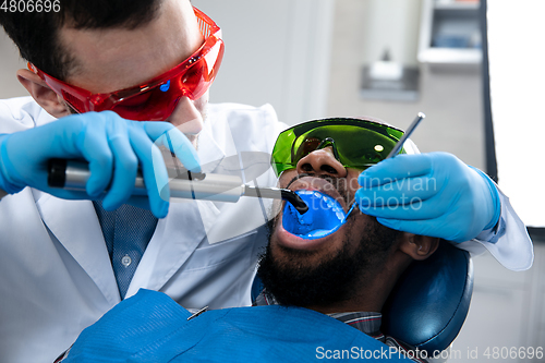 Image of Young african-american man visiting dentist\'s office