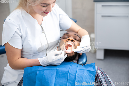 Image of Young african-american man visiting dentist\'s office