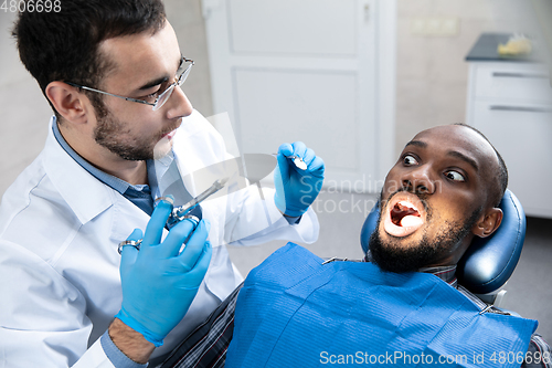 Image of Young african-american man visiting dentist\'s office