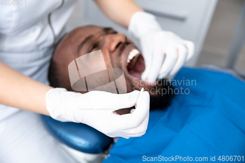 Image of Young african-american man visiting dentist\'s office, looks scared