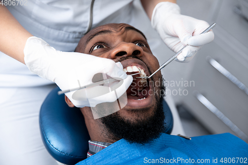 Image of Young african-american man visiting dentist\'s office