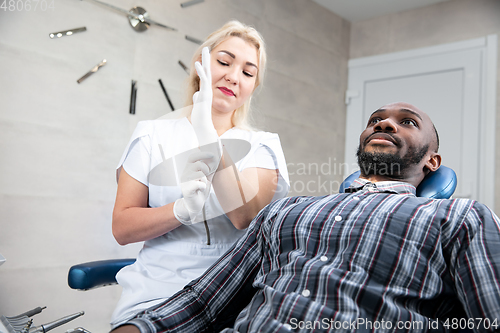 Image of Young african-american man visiting dentist\'s office