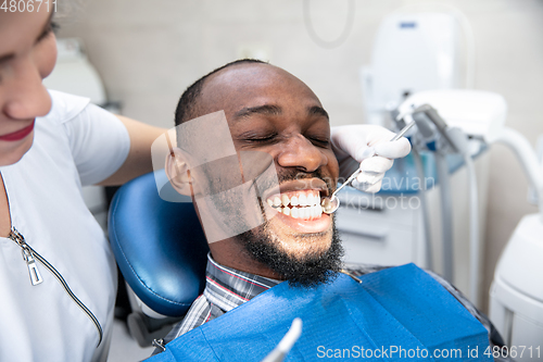Image of Young african-american man visiting dentist\'s office, smiling