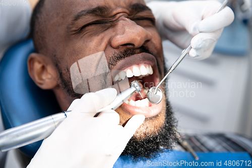 Image of Young african-american man visiting dentist\'s office, looks scared