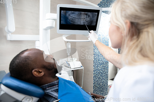 Image of Young african-american man visiting dentist\'s office