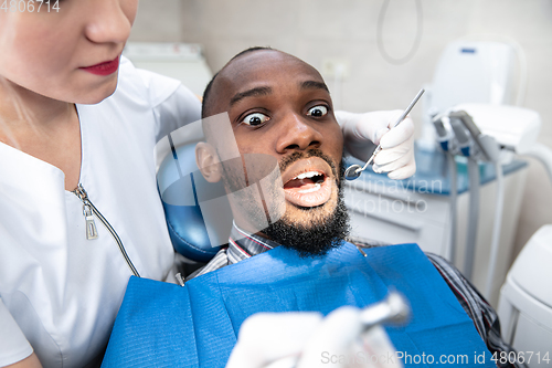 Image of Young african-american man visiting dentist\'s office