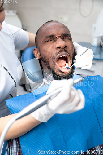 Image of Young african-american man visiting dentist\'s office, looks scared