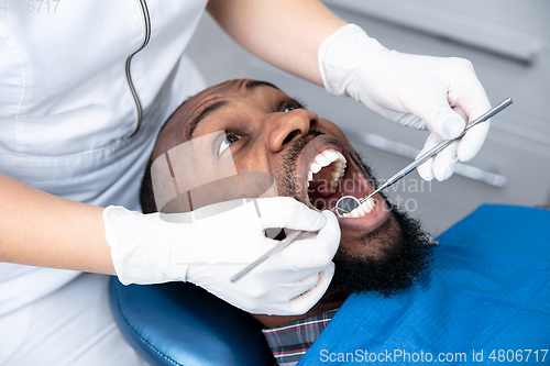 Image of Young african-american man visiting dentist\'s office