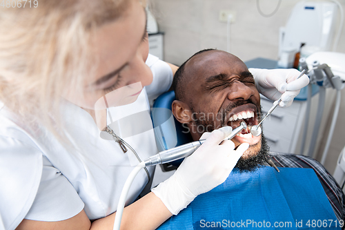 Image of Young african-american man visiting dentist\'s office