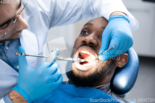 Image of Young african-american man visiting dentist\'s office