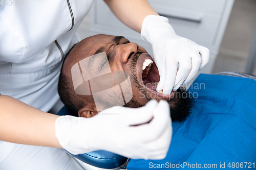 Image of Young african-american man visiting dentist\'s office, looks scared